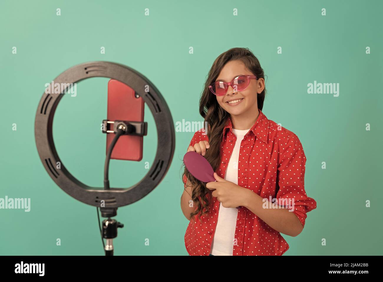 joyeux adolescent fille utiliser selfie led. enfant beauté blogueur. soins des cheveux. enfant dans des lunettes de soleil peignant les cheveux. Banque D'Images