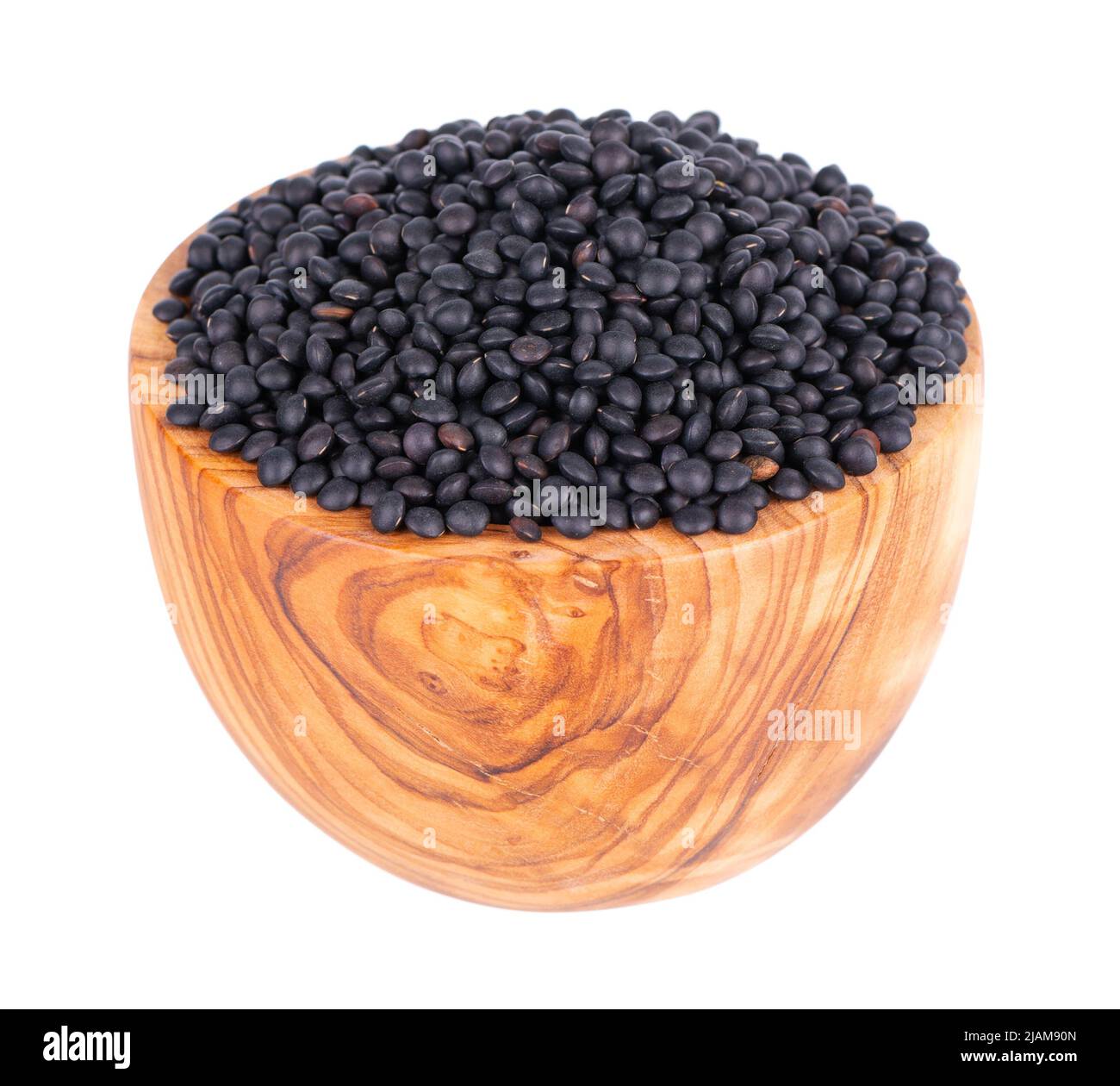 Lentilles noires dans un bol d'olive, isolées sur fond blanc. Pile de grains de lentilles de béluga secs Banque D'Images