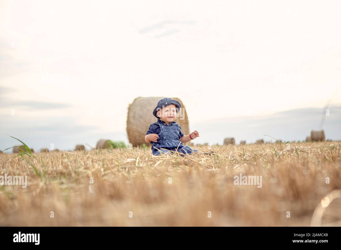 Petite belle fille souriante sur un champ de blé d'or. Banque D'Images