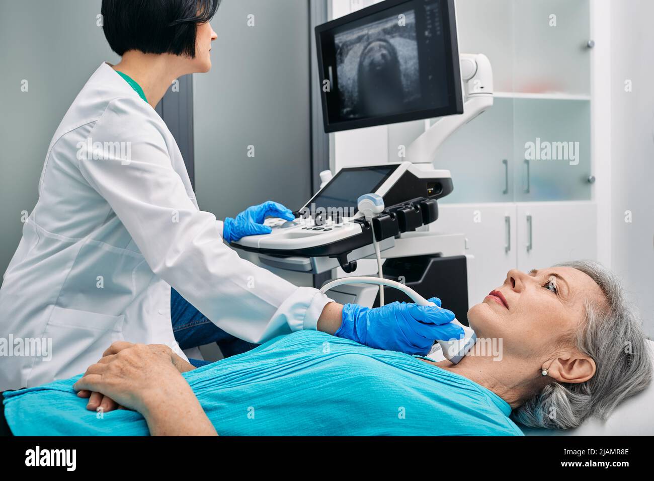 Diagnostic échographique de la glande thyroïde. Endocrinologue effectuant l'échographie à une patiente âgée au bureau d'échographie de la clinique médicale Banque D'Images