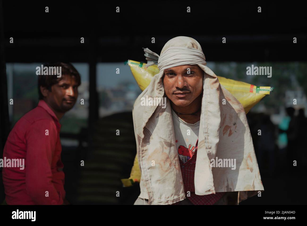 Portrait franc de l'homme employé pour déplacer de lourds sacs de ciment de la jonction de chemin de fer au camion d'attente à Mathura, Inde. Banque D'Images