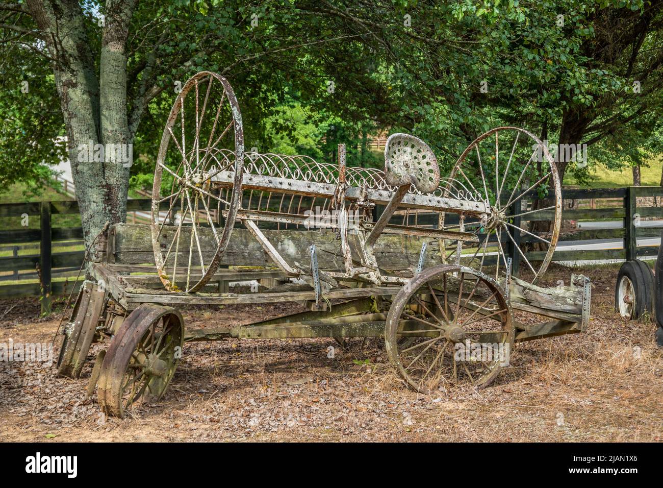 Vieux rateau de foin rouillé tiré par des chevaux sur un wagon cassé d'époque abandonné sur une ferme à l'extérieur par une journée ensoleillée Banque D'Images