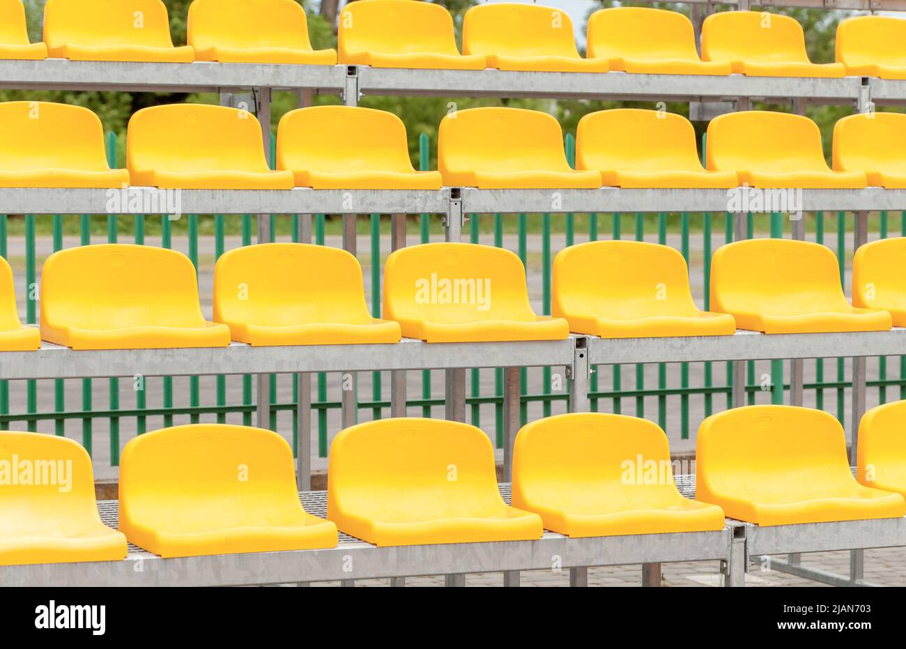 Vide statifs de stade vacants, chaises, sièges de spectateur d'aréna en plastique jaune, détail, petit terrain de football, jour, gros plan, personne. Événements sportifs Banque D'Images