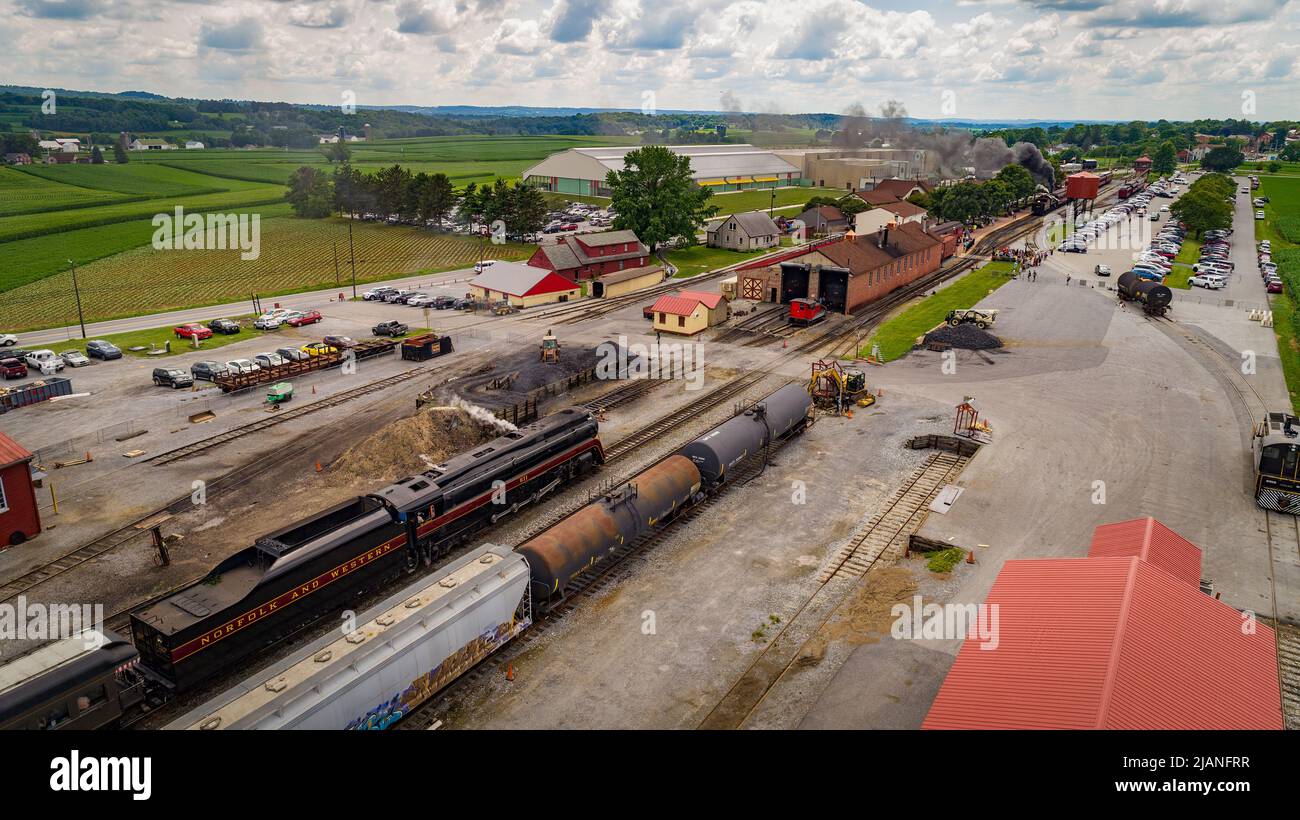 East Strasburg, Pennsylvanie, le 7 juillet 2021 - Drone View of a Steam Passenger train passant par un Freight Yard approchant d'une gare Banque D'Images
