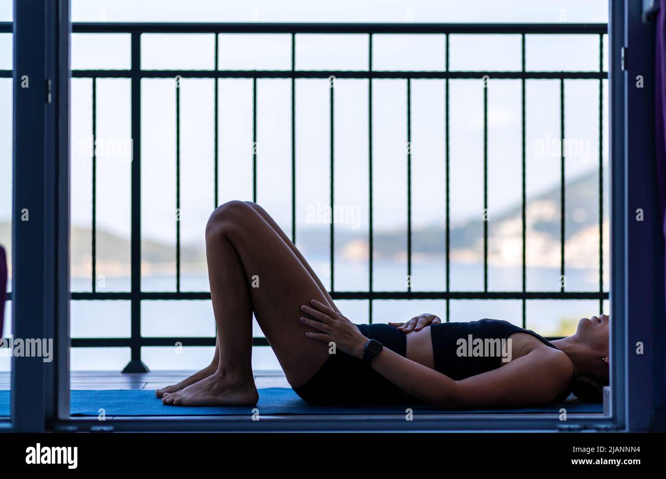 Jeune femme faisant son exercice de routine matinale au balcon le matin Banque D'Images