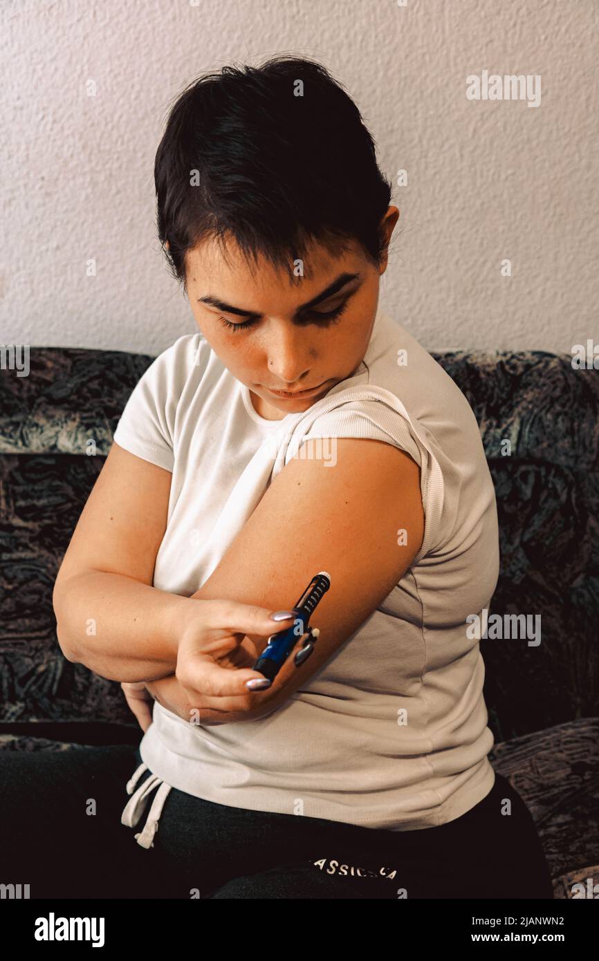une jeune fille aux cheveux noirs courts et au t-shirt blanc met l'insuline dans la main avec un stylo à insuline Banque D'Images