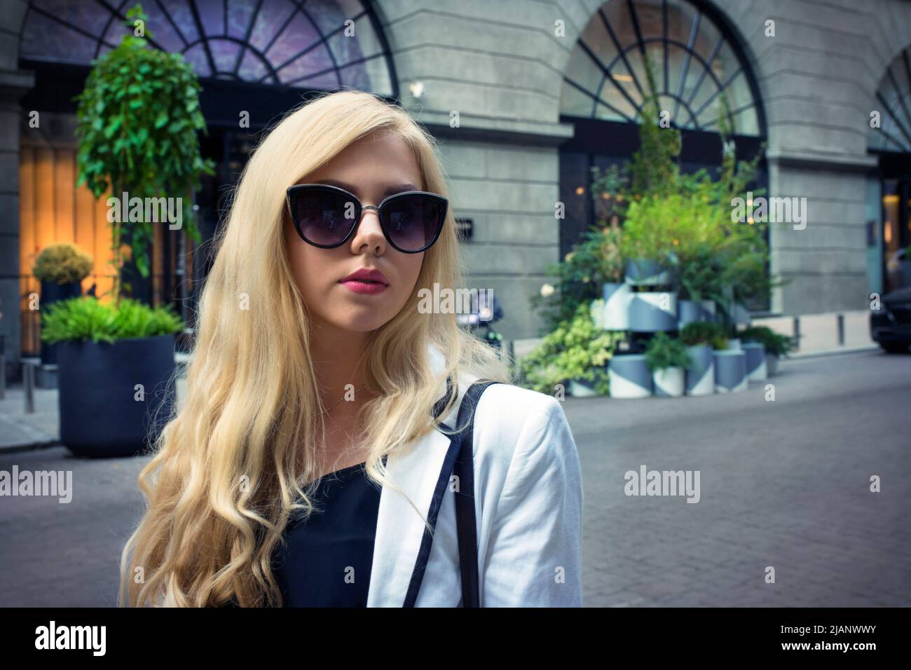 La jeune fille aux cheveux justes en lunettes de soleil sur le fond de la rue vide. Banque D'Images