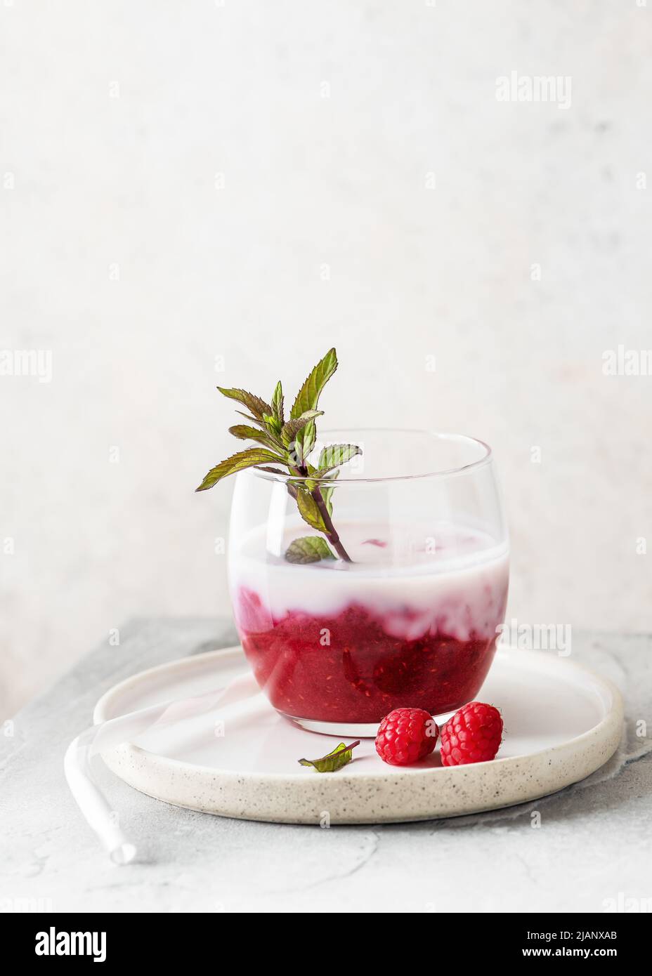 Smoothie au babeurre fait maison avec confiture de framboises et branche de menthe poivrée dans un verre. Concept de nourriture saine et sucrée espace de copie. Banque D'Images