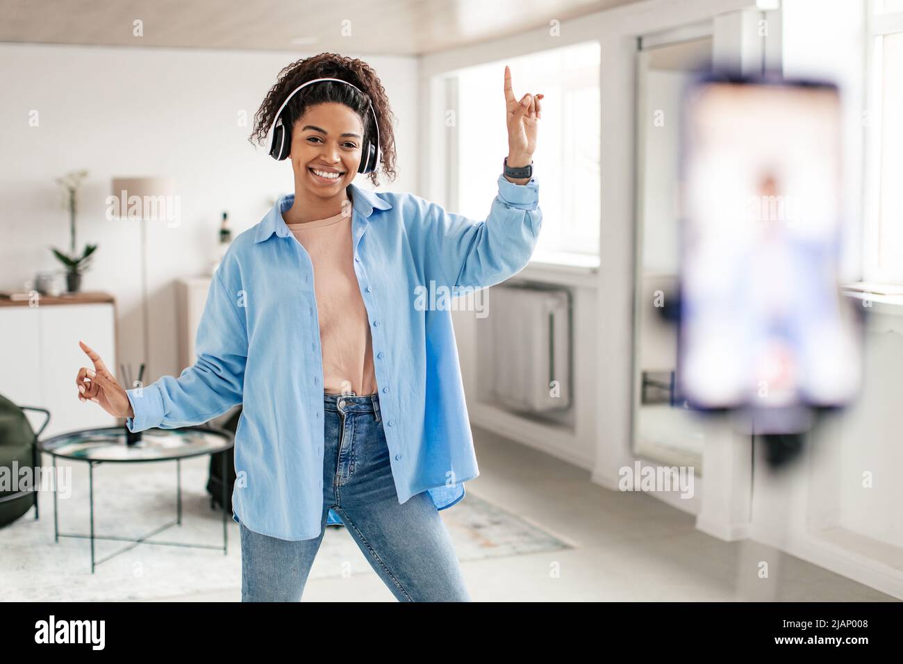 Une femme noire gaie filmant des vidéos de danse sur un téléphone portable Banque D'Images