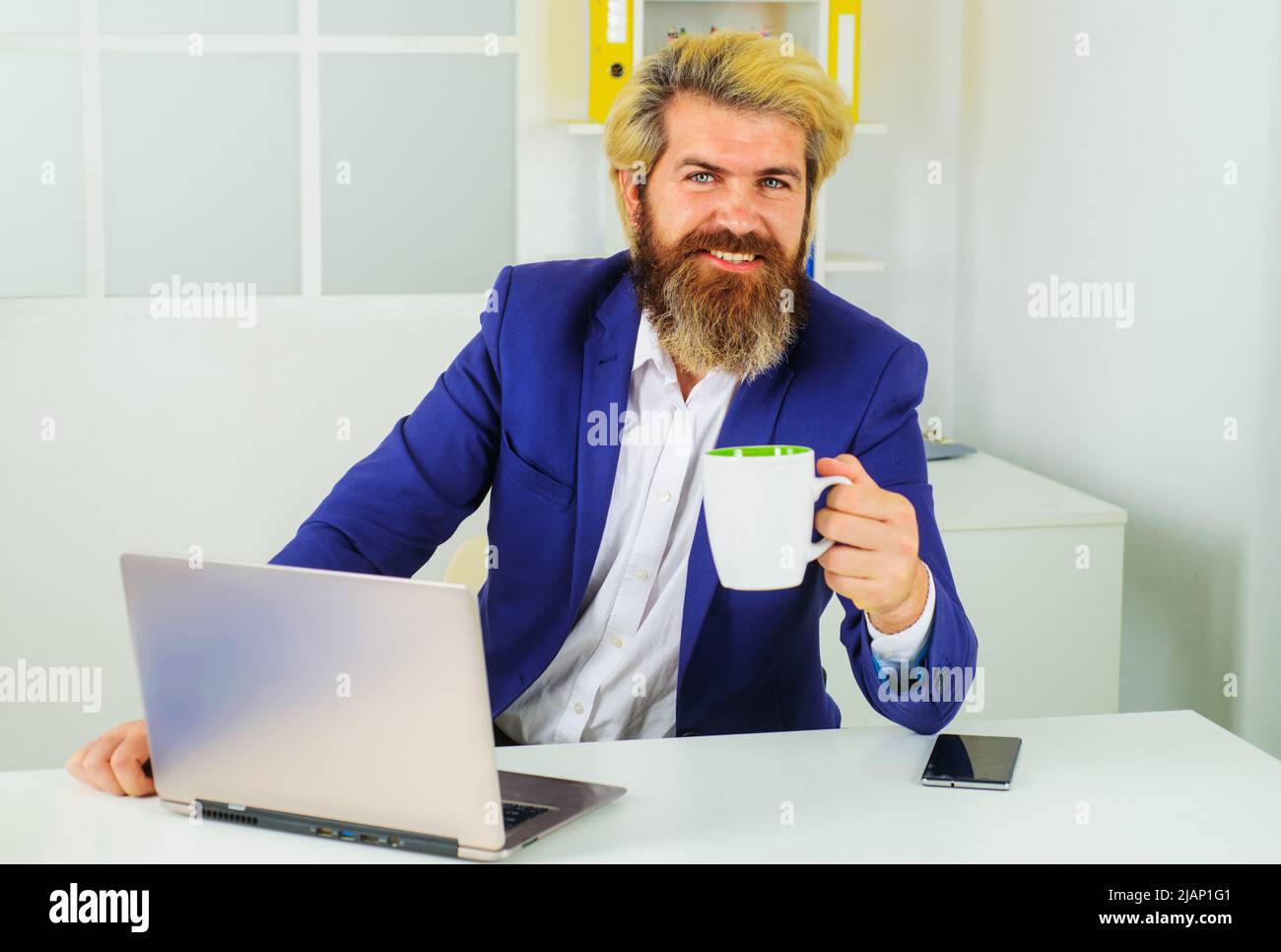 Homme d'affaires travaillant avec un ordinateur portable au bureau pour une pause-café. Entrepreneur avec une tasse de cappuccino. Banque D'Images