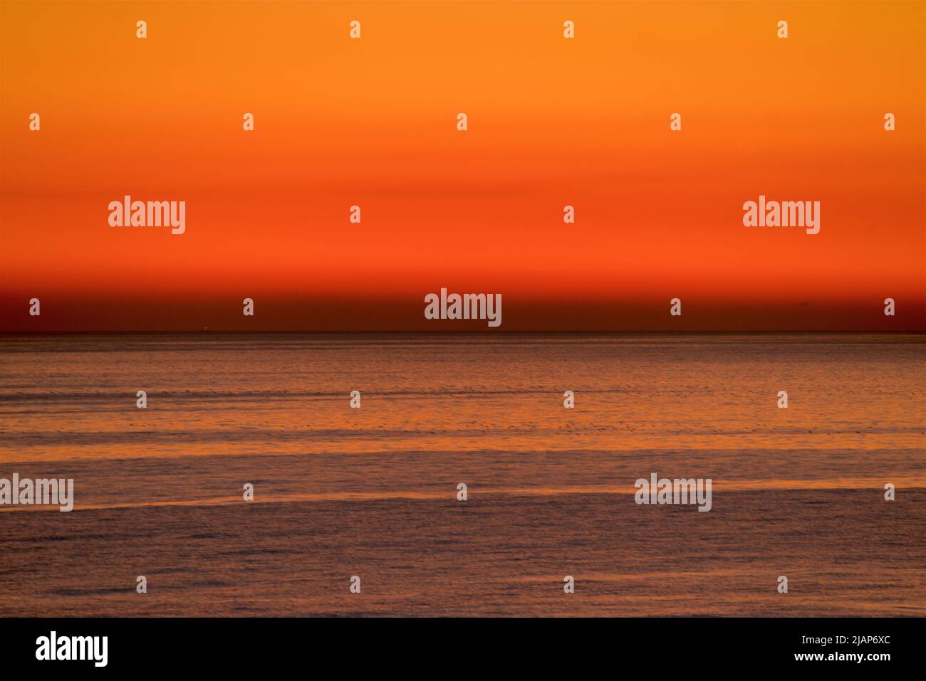 Détail des ondulations sur une mer calme avec un horizon sombre et doré au-delà. Chaîne anglaise, Royaume-Uni. Banque D'Images