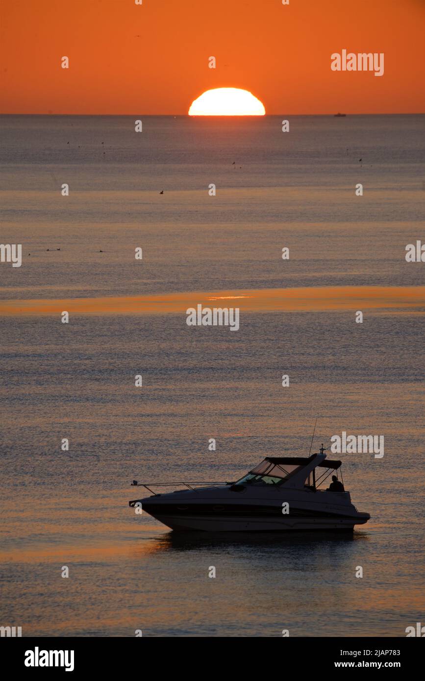 Forme silhouetée d'un petit bateau à moteur amarré en mer. Eau calme, canal anglais. Réglage du soleil. Brighton, Angleterre, Royaume-Uni Banque D'Images