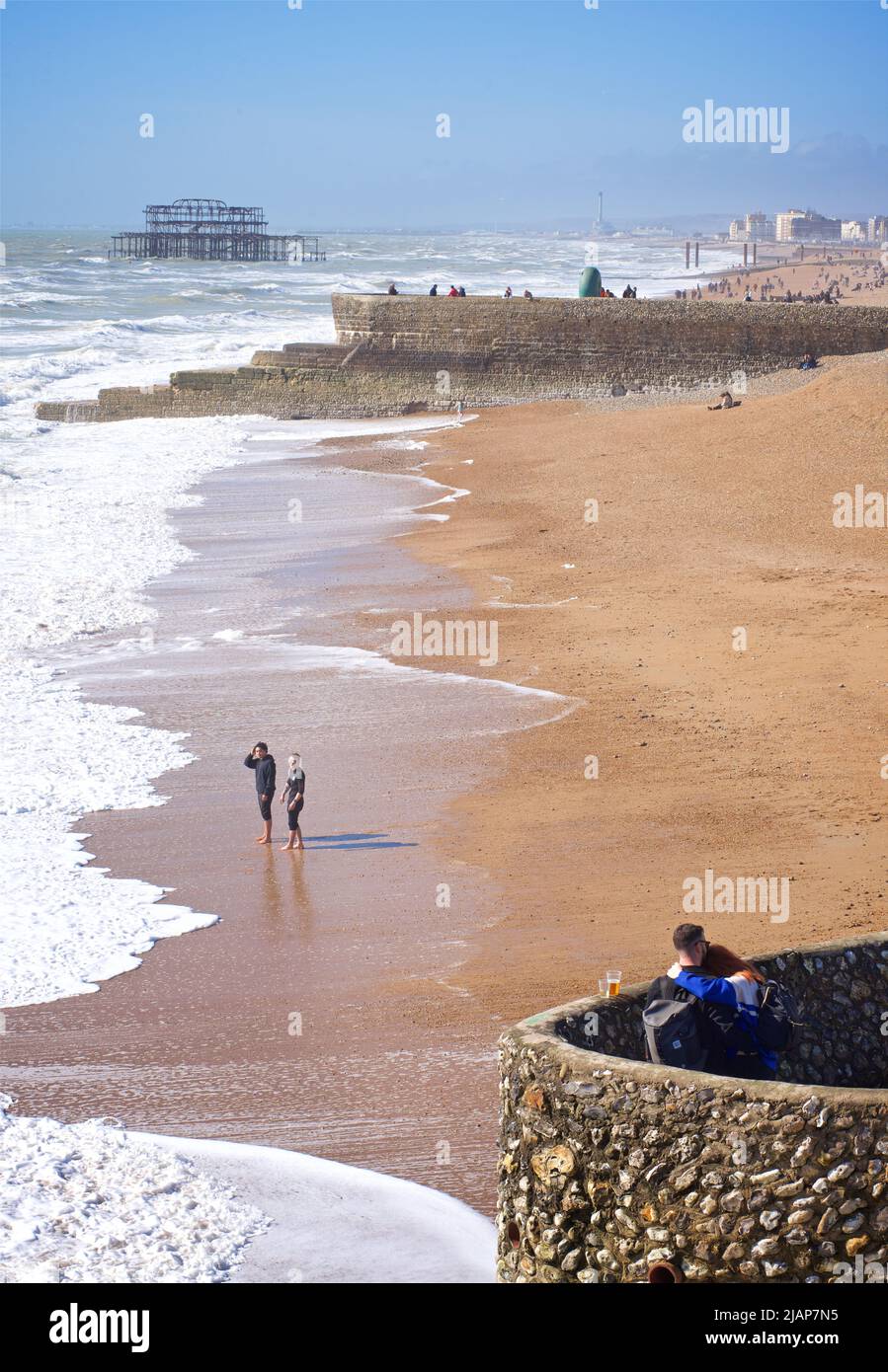 La plage de Brighton et les vestiges de la jetée ouest au-delà lors d'une journée ensoleillée de mars. Les gens sur la groyne et la plage au-delà. Brighton, Brighton & Hove, East Sussex, Angleterre, Royaume-Uni Banque D'Images