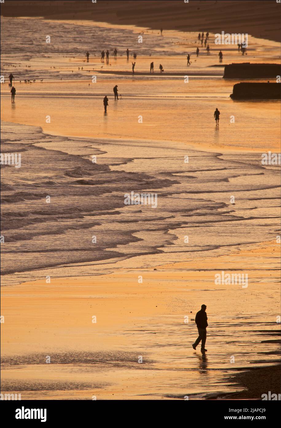 Silhoueted formes de personnes sur la plage à marée basse, Brighton & Hove, East Sussex, Angleterre, Royaume-Uni. Banque D'Images
