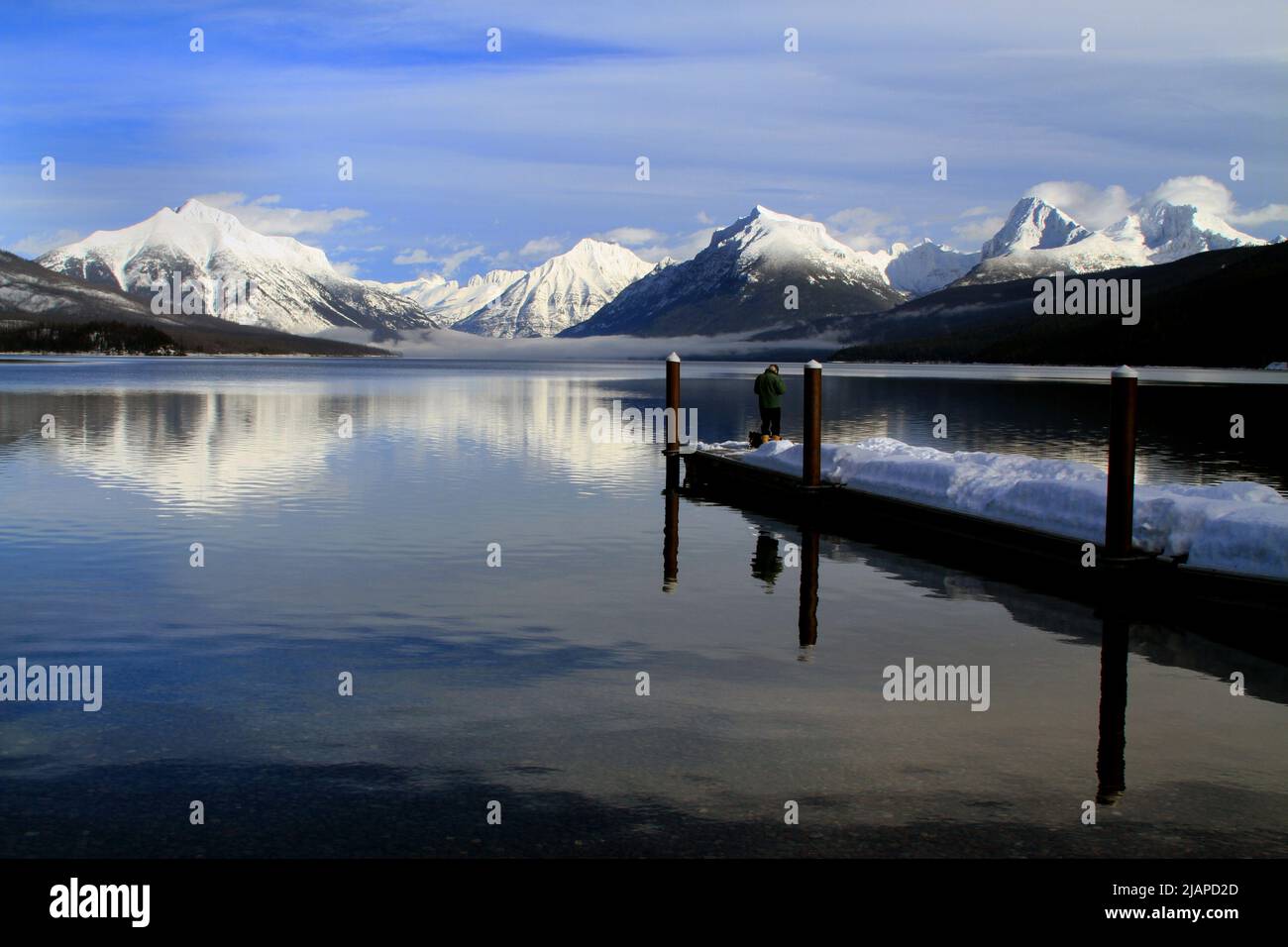 Un homme pêchant sur le lac McDonald en hiver. Le lac McDonald est le plus grand lac du parc national des Glaciers. Il est situé dans le comté de Flathead, dans le Montana, aux États-Unis d'Amérique. Le lac est d'environ 10 milles de long, et plus d'un mille de large et 472 pieds de profondeur, remplissant une vallée formée par une combinaison d'érosion et d'activité glaciaire. Une version unique et optimisée d'une image NPS, crédit : NPS/D.Restivo Banque D'Images