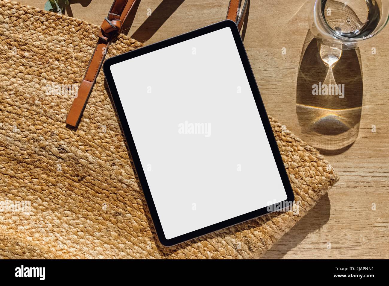 Maquette de tablette, appareil noir avec écran blanc vide sur la table en bois, en plein soleil, vue du dessus Banque D'Images