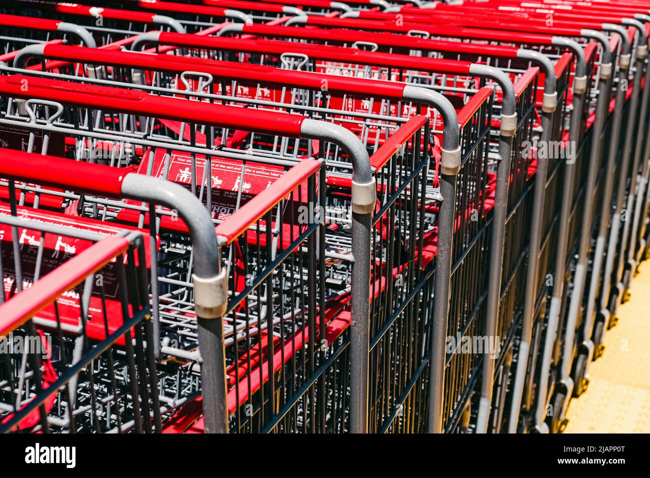 Gros plan des chariots de supermarché en métal avec poignées rouges dans la rue Banque D'Images