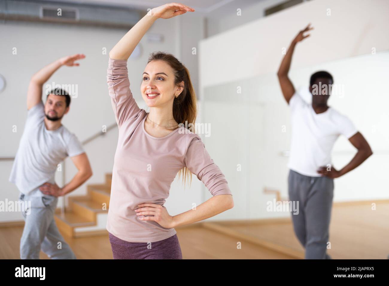 Femme pratiquant des mouvements de danse classique pendant la classe de groupe Banque D'Images