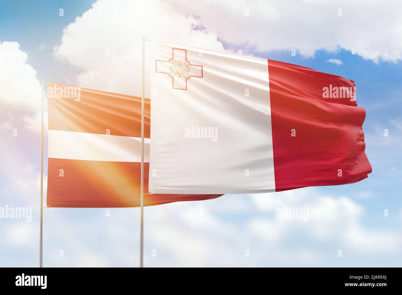 Ciel bleu ensoleillé et drapeaux de malte et de lettonie Banque D'Images