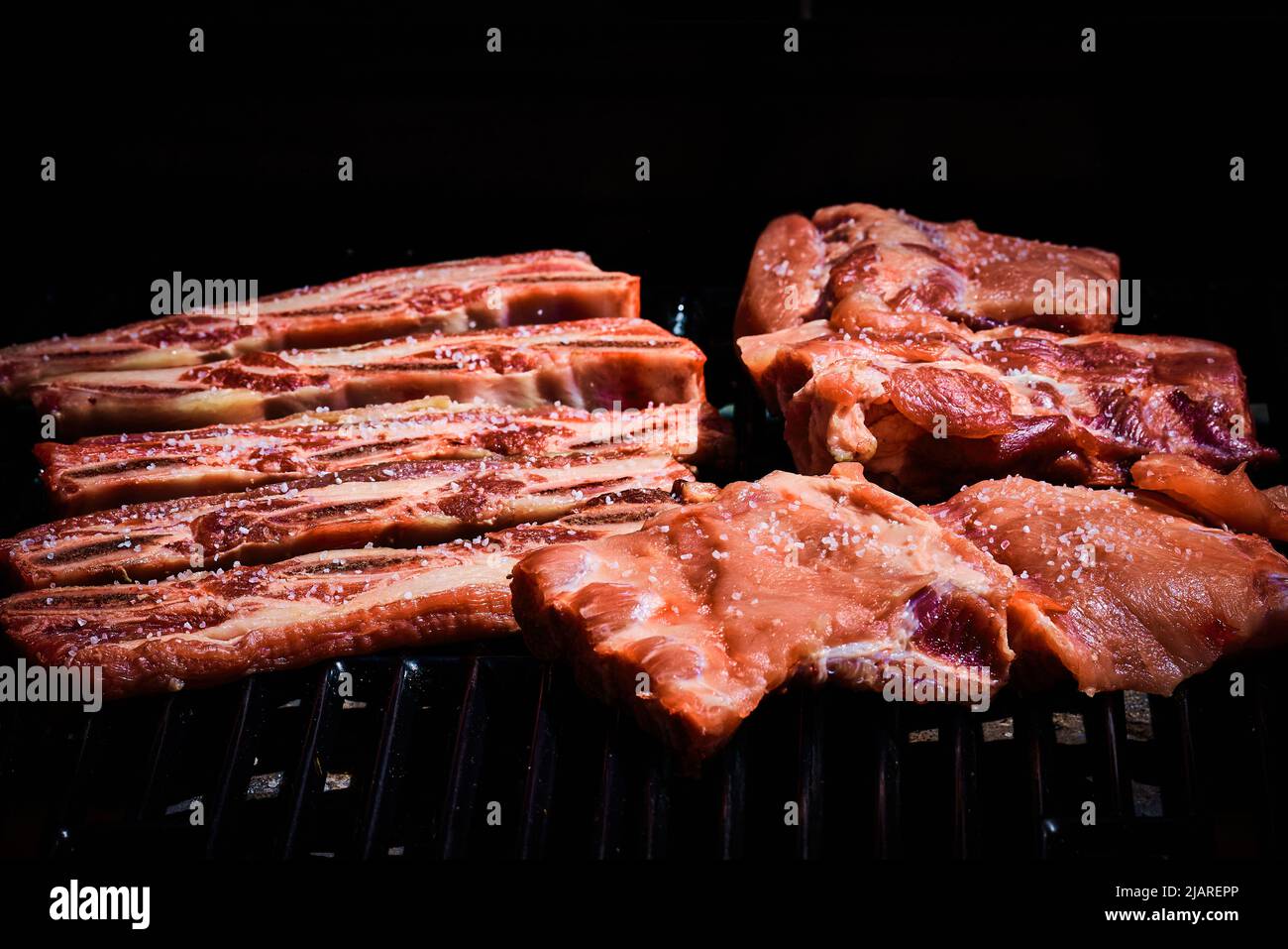 Côtes de bœuf et côtes de porc fraîchement posées sur le barbecue pour commencer à griller Banque D'Images