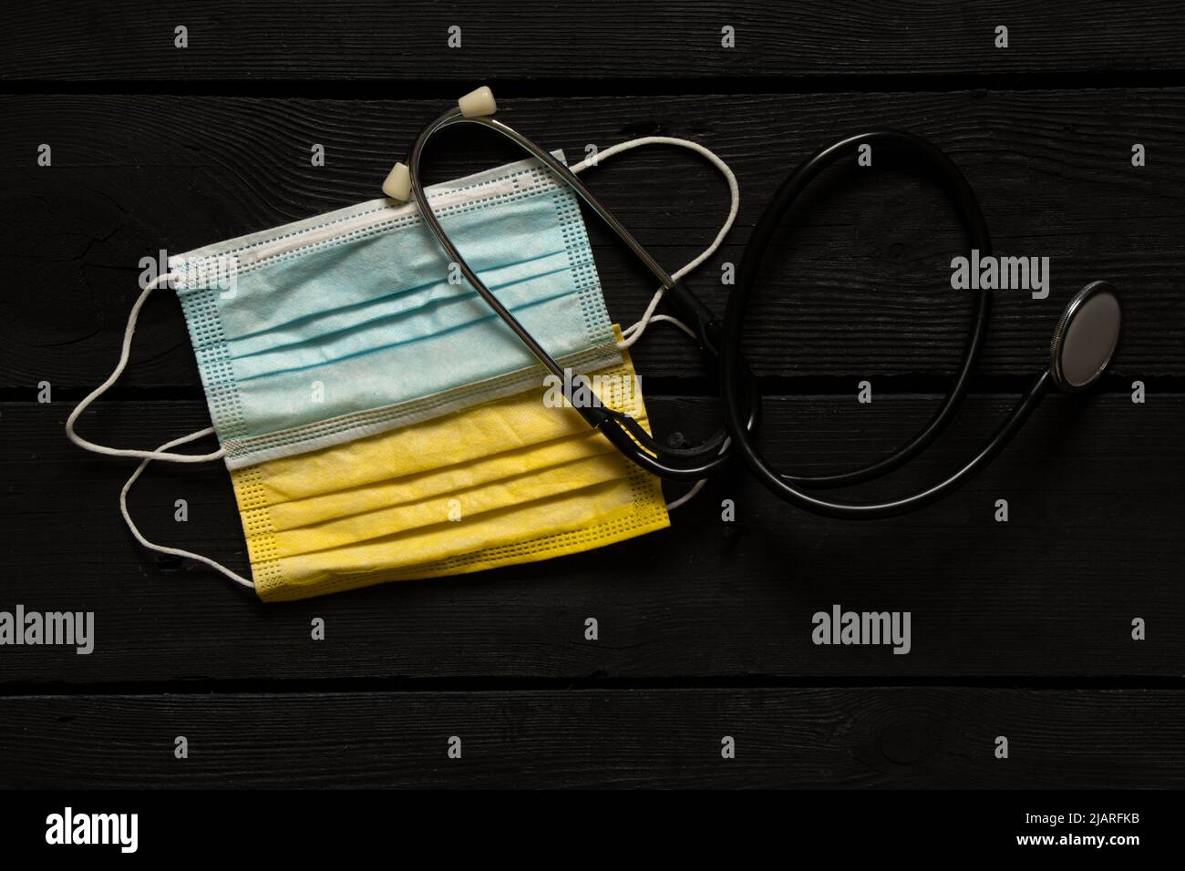 Des masques médicaux jaune-bleu comme le drapeau de l'Ukraine et un stéthoscope se trouvent sur une table en bois. Drapeau d'Etat de l'Ukraine, arrêter la guerre. La Russie est en passe de l’être Banque D'Images
