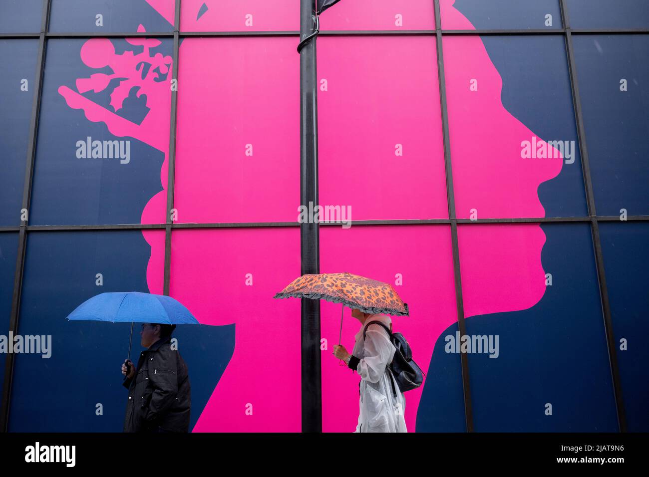 Deux Londoniens marchent sous une silhouette géante de la tête de la Reine devant Coutts Bank sur le Strand alors que les préparatifs se poursuivent pour les célébrations du Jubilé de platine de la Reine dans la capitale, le 31st mai 2022, à Londres, en Angleterre. La reine Elizabeth II est sur le trône du Royaume-Uni depuis 70 ans, le monarque le plus longtemps au service de l'histoire anglaise et les drapeaux de l'Union Jack peuvent être vus partout dans le pays dans la semaine précédant le week-end du Jubilé. Banque D'Images