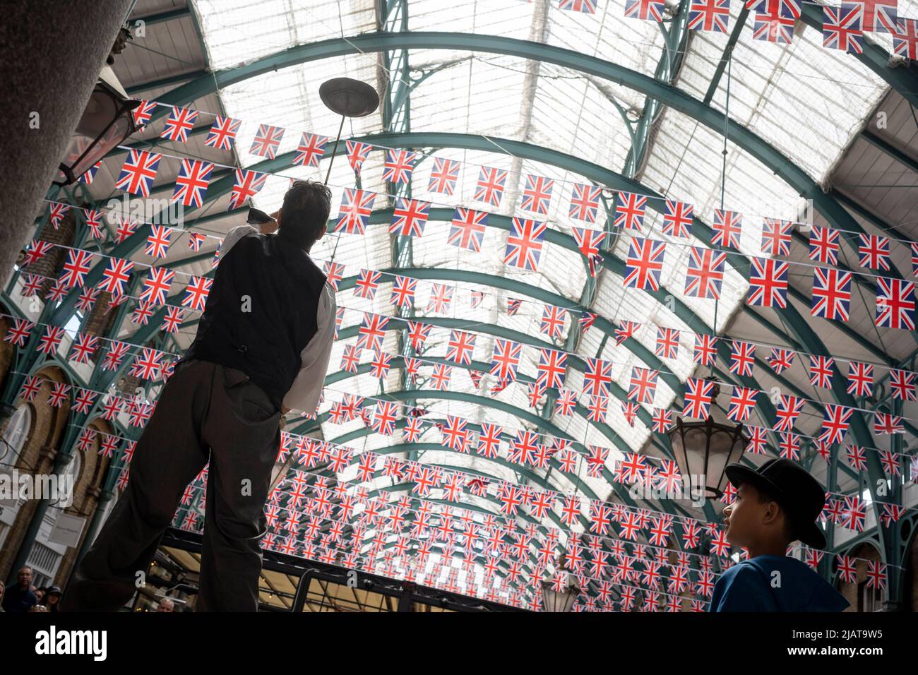 Un animateur de rue se produit devant les foules à Covent Garden alors que les préparatifs se poursuivent pour les célébrations du Jubilé de platine de la Reine dans la capitale, le 31st mai 2022, à Londres, en Angleterre. La reine Elizabeth II est sur le trône du Royaume-Uni depuis 70 ans, le monarque le plus longtemps au service de l'histoire anglaise et les drapeaux de l'Union Jack peuvent être vus partout dans le pays dans la semaine précédant le week-end du Jubilé. Banque D'Images