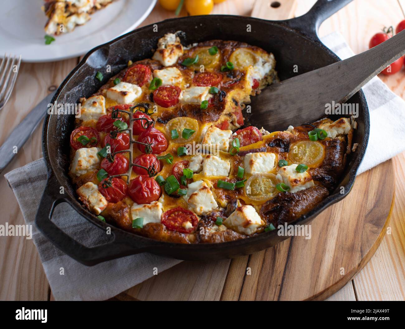 Frittata avec tomates, poivrons, oignons et feta dans une poêle rustique Banque D'Images