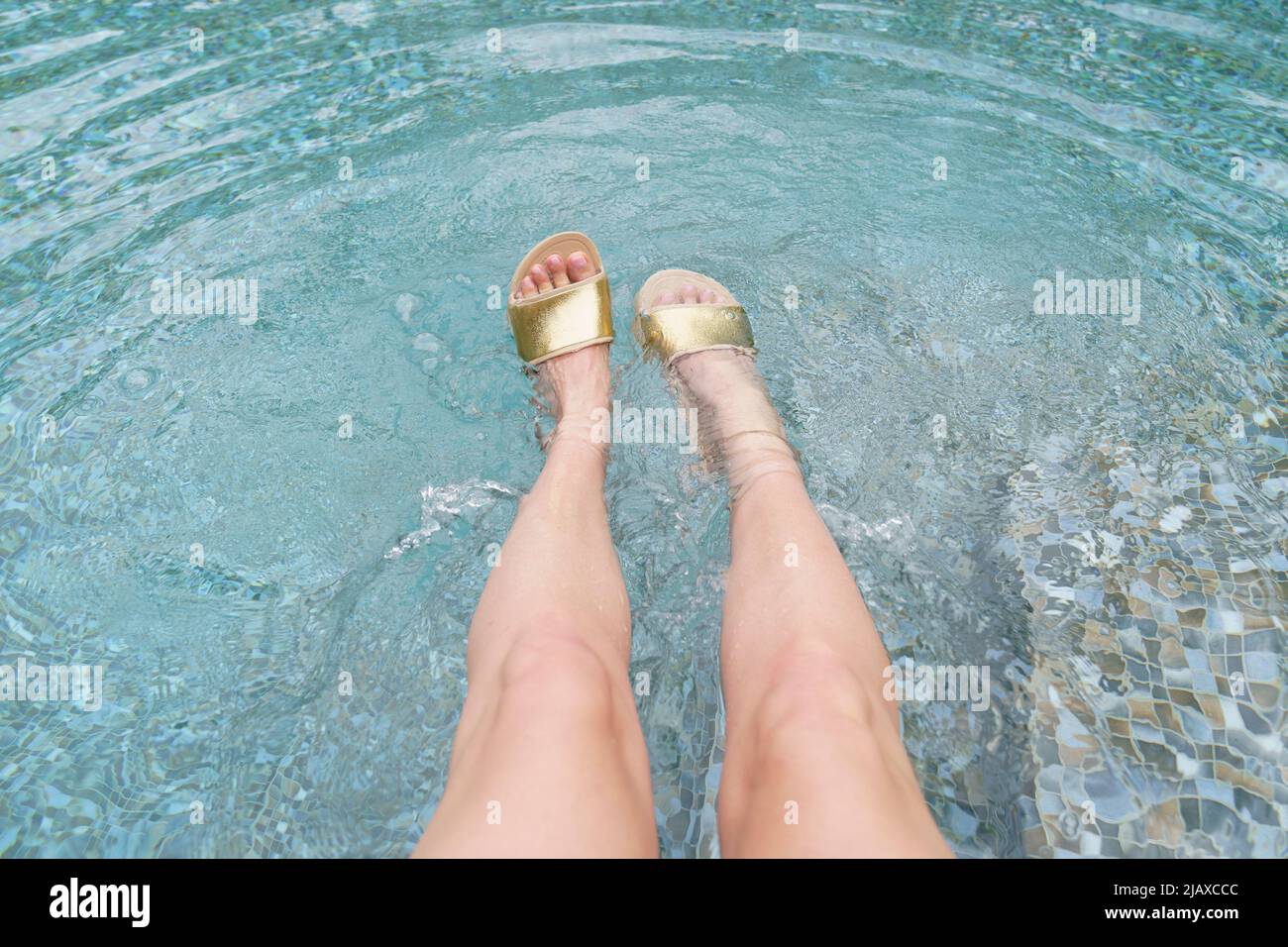 Les pieds des femmes dans les tongs dans la piscine. Banque D'Images