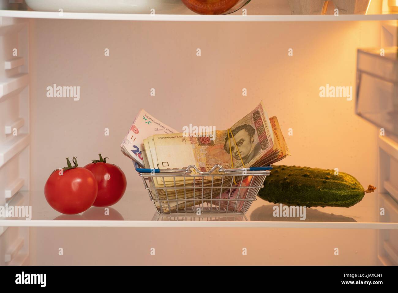 Cent deux cents hryvnia dans un panier d'un supermarché sur les étagères dans le réfrigérateur à côté de tomates et concombres dans la cuisine, u Banque D'Images