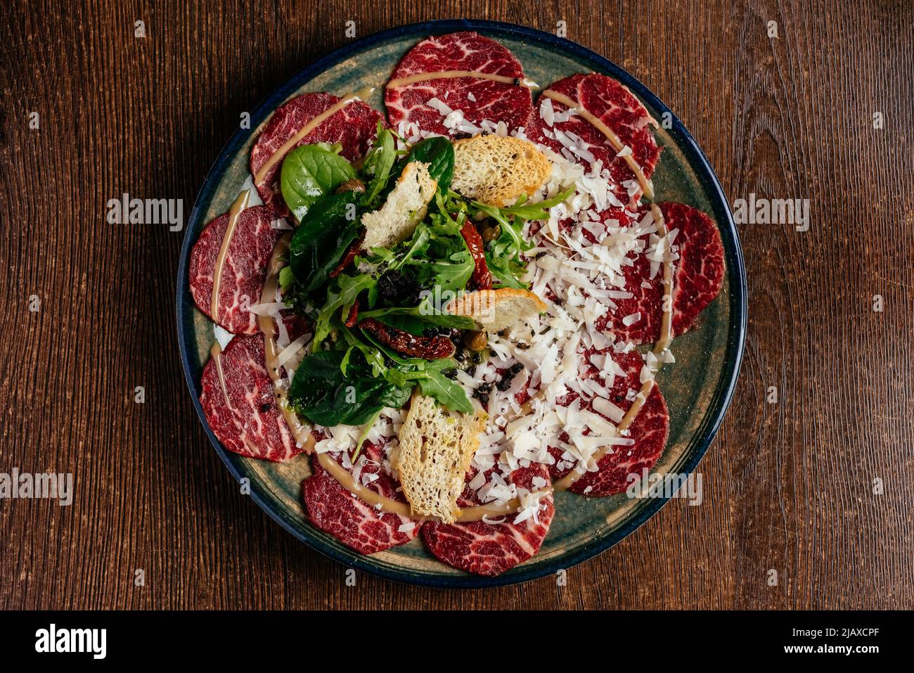 carpaccio de bœuf en marbre sur une assiette avec sauce et herbes Banque D'Images