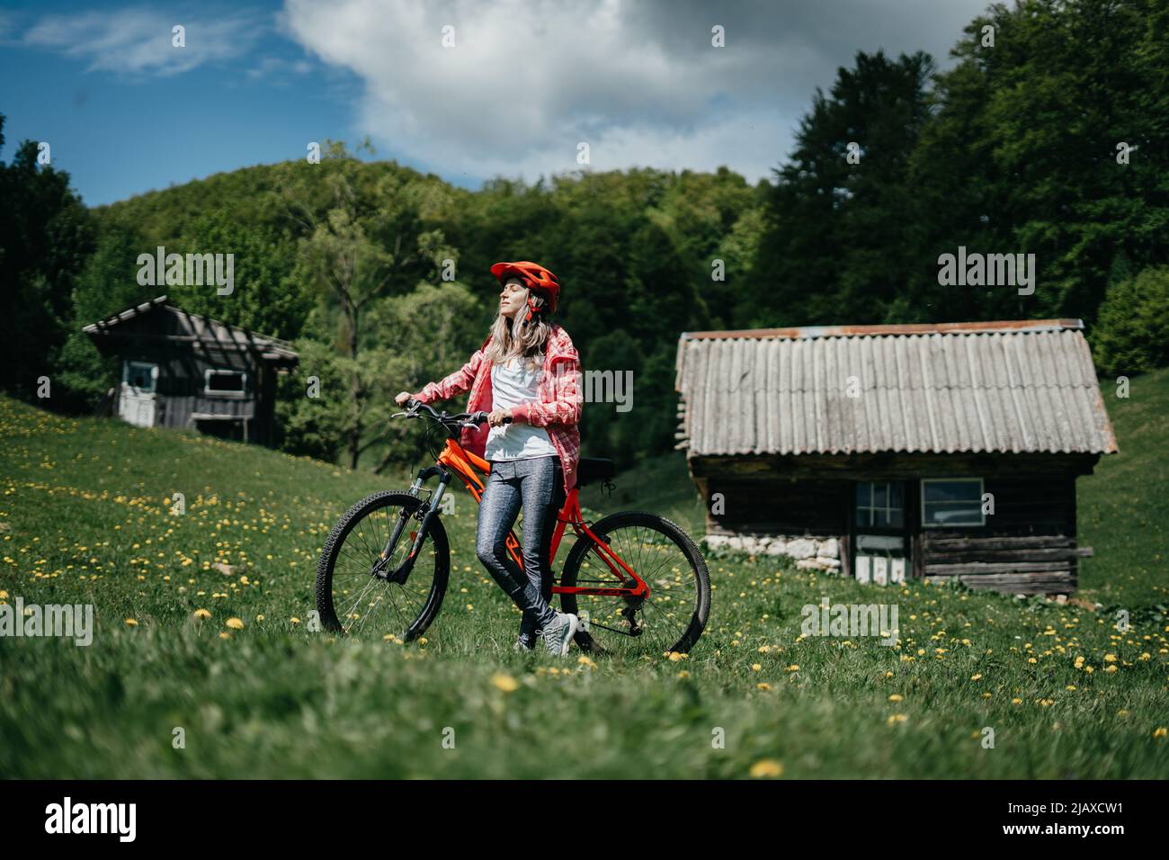 La jeune fille est assise sur son vélo face au soleil dans la nature Banque D'Images