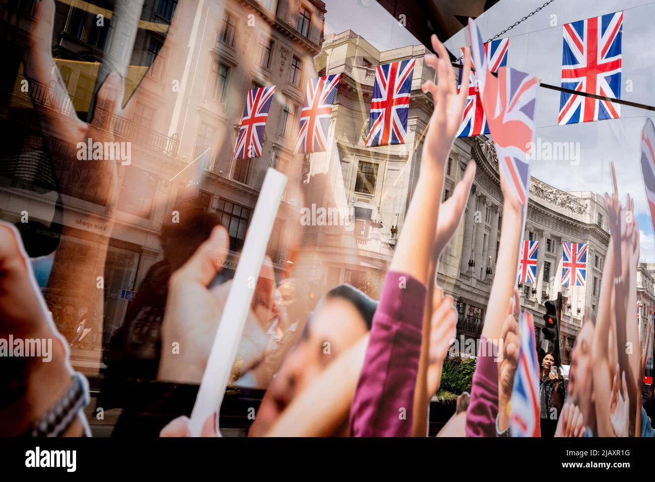 Des images d'armes de célébration en l'air forment une vitrine, qui fait partie des célébrations du Jubilé de platine de la Reine dans la fenêtre du détaillant « Hackett », qui se mêle à un arrière-plan des acheteurs et des drapeaux de Union Jack au-dessus de Regent Street, le 1st juin 2022 à Londres, en Angleterre. La reine Elizabeth II est sur le trône du Royaume-Uni depuis 70 ans, le monarque le plus longtemps au service de l'histoire anglaise et les drapeaux de l'Union Jack peuvent être vus partout dans le pays dans la semaine précédant le week-end du Jubilé. Banque D'Images