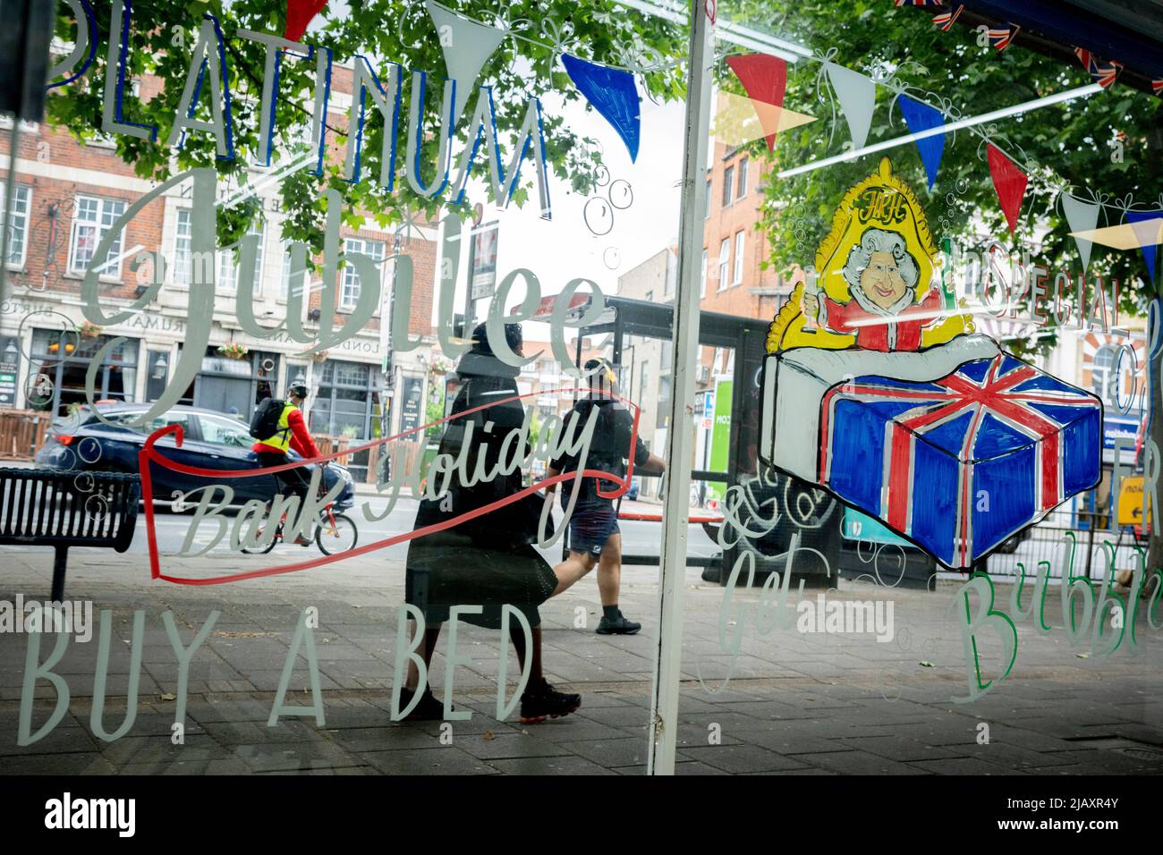 Une peinture montrant la Reine au lit est sur la fenêtre d'un magasin de lit et de meubles sur la route Walworth dans le sud de Londres, le 1st juin 2022 à Londres, Angleterre. La reine Elizabeth II est sur le trône du Royaume-Uni depuis 70 ans, le monarque le plus longtemps au service de l'histoire anglaise et les drapeaux de l'Union Jack peuvent être vus partout dans le pays dans la semaine précédant le week-end du Jubilé. Banque D'Images