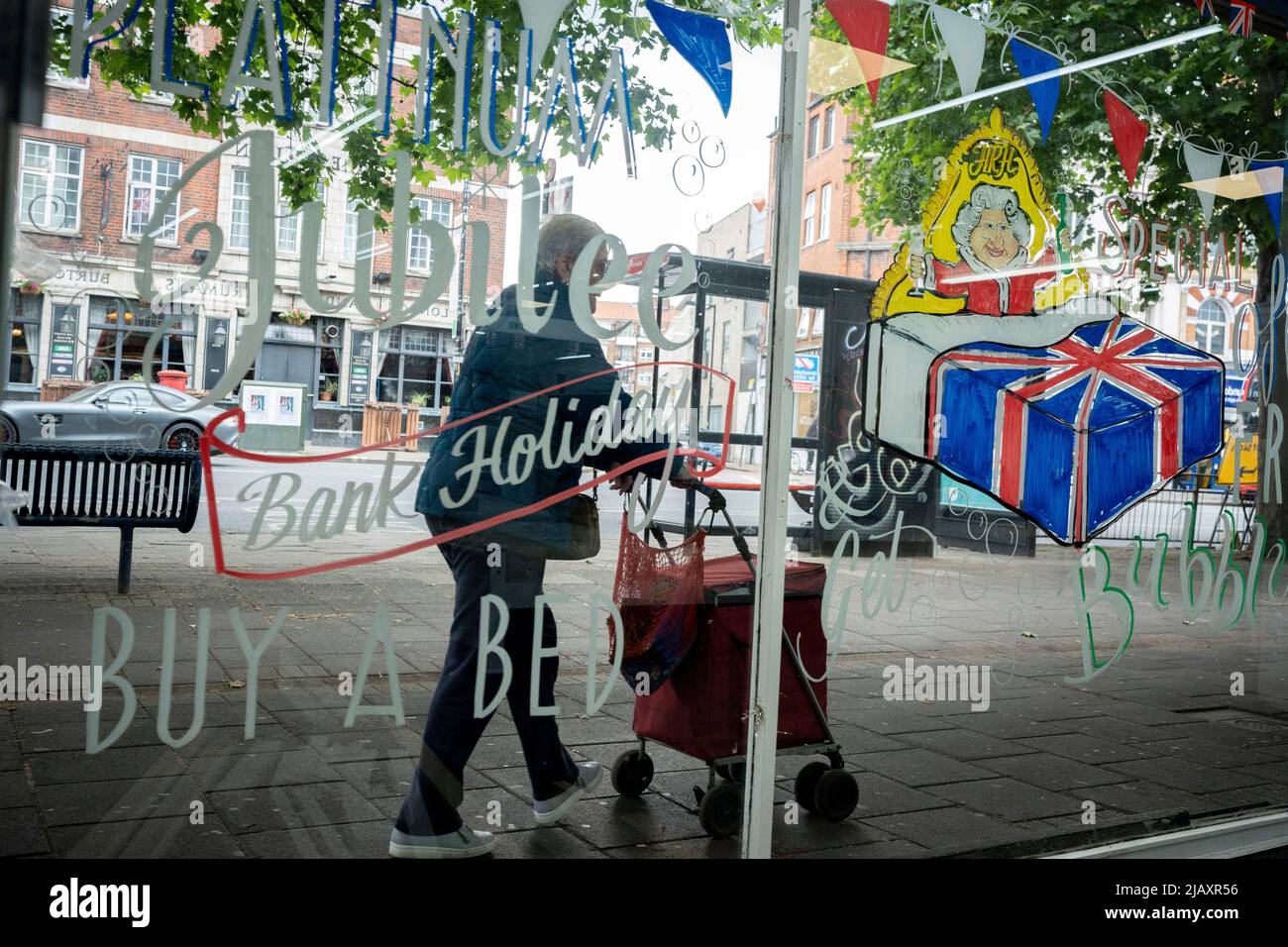 Une peinture montrant la Reine au lit est sur la fenêtre d'un magasin de lit et de meubles sur la route Walworth dans le sud de Londres, le 1st juin 2022 à Londres, Angleterre. La reine Elizabeth II est sur le trône du Royaume-Uni depuis 70 ans, le monarque le plus longtemps au service de l'histoire anglaise et les drapeaux de l'Union Jack peuvent être vus partout dans le pays dans la semaine précédant le week-end du Jubilé. Banque D'Images