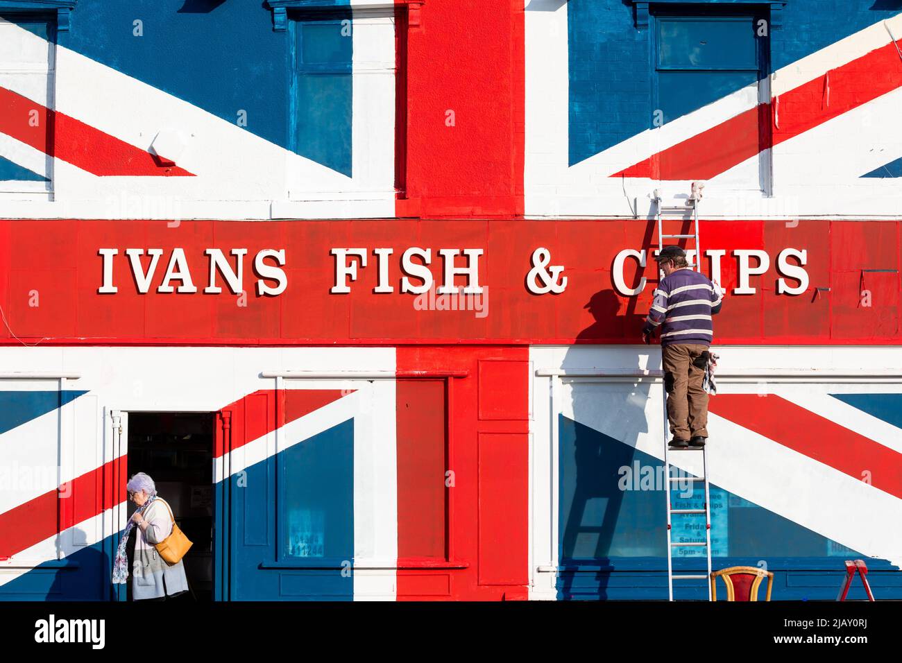 Cradley Heath, West Midlands, Royaume-Uni. 1st juin 2022. Warren Rudge, le propriétaire de la boutique de jetons, ajoute la touche finale à l'Union Jackflag que lui et son fils James ont peint sur leur boutique de poissons et de jetons à Cradley Heath, West Midlands. Le drapeau peint couvre l'ensemble de la façade de poisson et de frites d'Ivan, y compris les fenêtres, et a pris toute la journée à compléter. 'Ivan's Fish and Chips sert du poisson et des chips depuis 65 ans - pas aussi longtemps que sa Majesté cependant. Mais j'ai entendu dire que la Reine est partielle pour pêcher et pêcher des frites." dit Warren. Crédit : Peter Lophan/Alay Live News Banque D'Images
