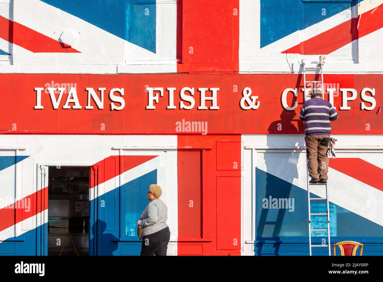 Cradley Heath, West Midlands, Royaume-Uni. 1st juin 2022. Warren Rudge, le propriétaire de la boutique de jetons, ajoute la touche finale à l'Union Jackflag que lui et son fils James ont peint sur leur boutique de poissons et de jetons à Cradley Heath, West Midlands. Le drapeau peint couvre l'ensemble de la façade de poisson et de frites d'Ivan, y compris les fenêtres, et a pris toute la journée à compléter. 'Ivan's Fish and Chips sert du poisson et des chips depuis 65 ans - pas aussi longtemps que sa Majesté cependant. Mais j'ai entendu dire que la Reine est partielle pour pêcher et pêcher des frites." dit Warren. Crédit : Peter Lophan/Alay Live News Banque D'Images