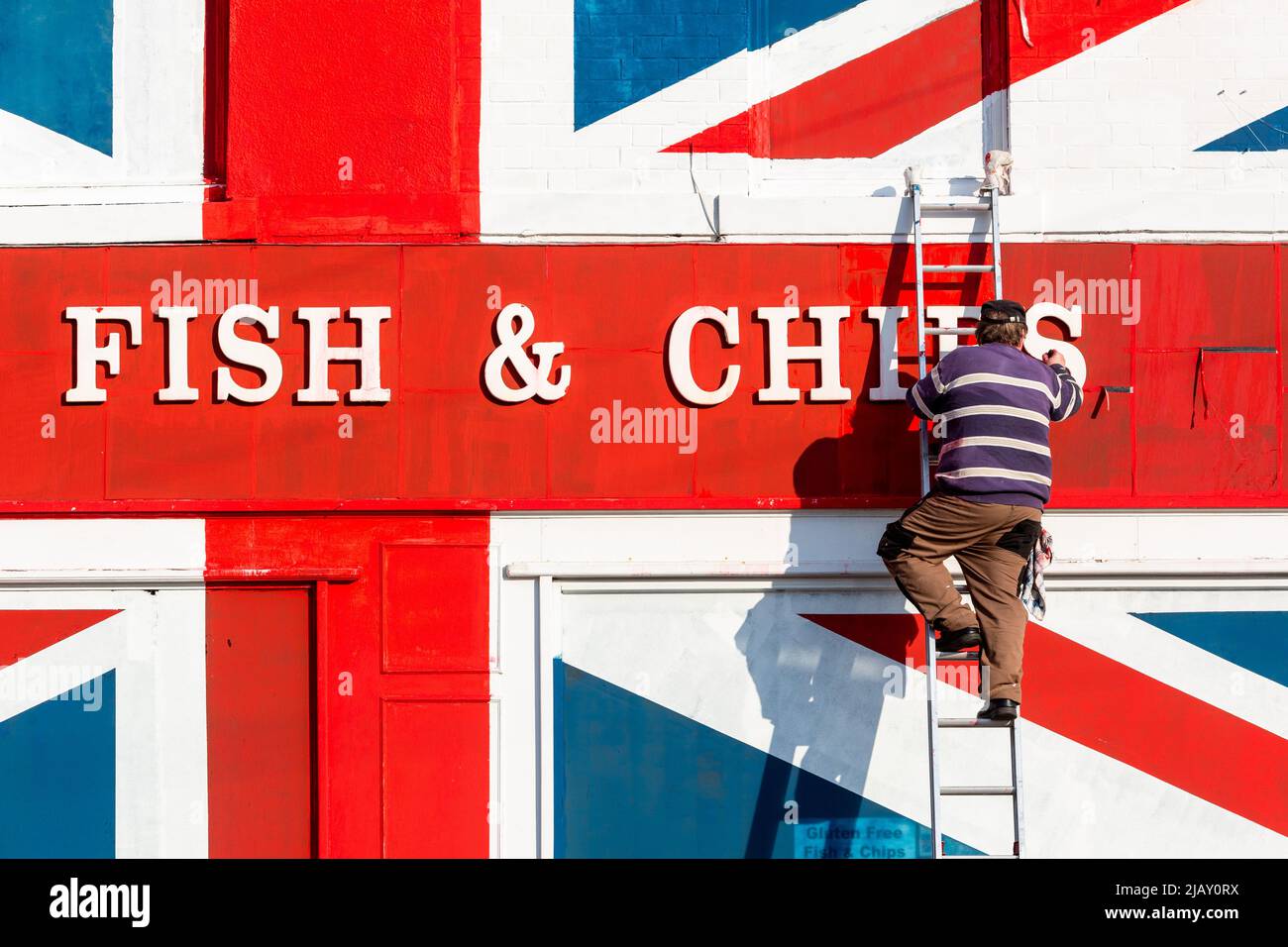 Cradley Heath, West Midlands, Royaume-Uni. 1st juin 2022. Warren Rudge, le propriétaire de la boutique de jetons, ajoute la touche finale à l'Union Jackflag que lui et son fils James ont peint sur leur boutique de poissons et de jetons à Cradley Heath, West Midlands. Le drapeau peint couvre l'ensemble de la façade de poisson et de frites d'Ivan, y compris les fenêtres, et a pris toute la journée à compléter. 'Ivan's Fish and Chips sert du poisson et des chips depuis 65 ans - pas aussi longtemps que sa Majesté cependant. Mais j'ai entendu dire que la Reine est partielle pour pêcher et pêcher des frites." dit Warren. Crédit : Peter Lophan/Alay Live News Banque D'Images