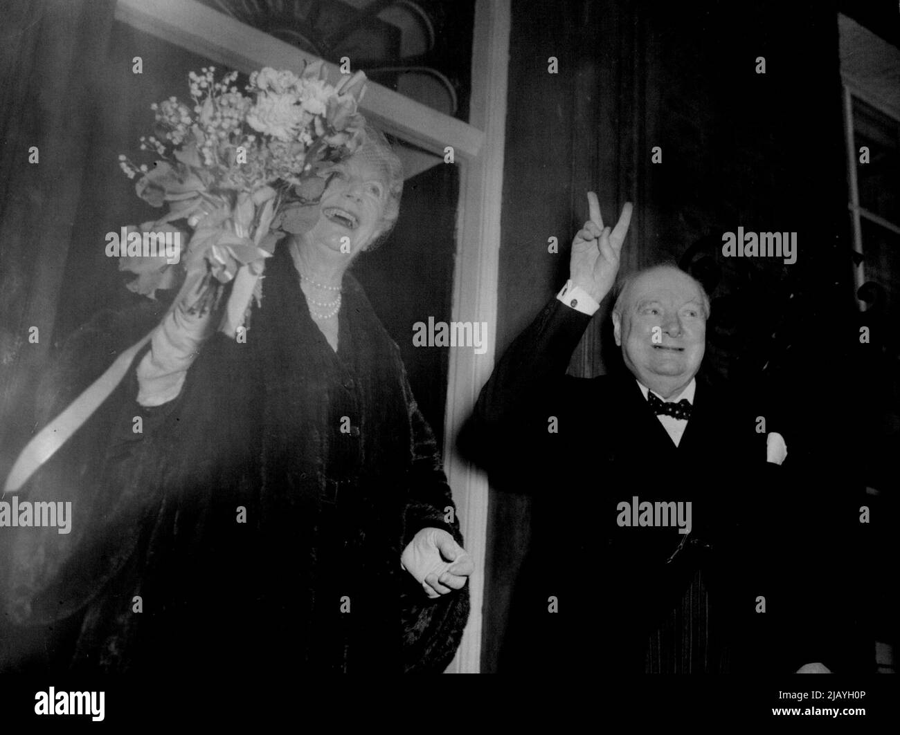 Merci pour Un joyeux anniversaire: À la salle Westminster, Sir Winston avait reçu un portrait de lui-même - le cadeau uni du Parlement à son anniversaire. L'une des images les plus heureuses de ses quatre années de carrière comme Sir Winston Churchill chuchote et donne son célèbre signe « V » tandis que Lady Churchill fait un grand vagues de son bouquet de la réponse aux foules rassemblées pour saluer le premier ministre à son retour de la salle Westminster. 30 novembre 1954. (Photo de Reuterphoto). Banque D'Images