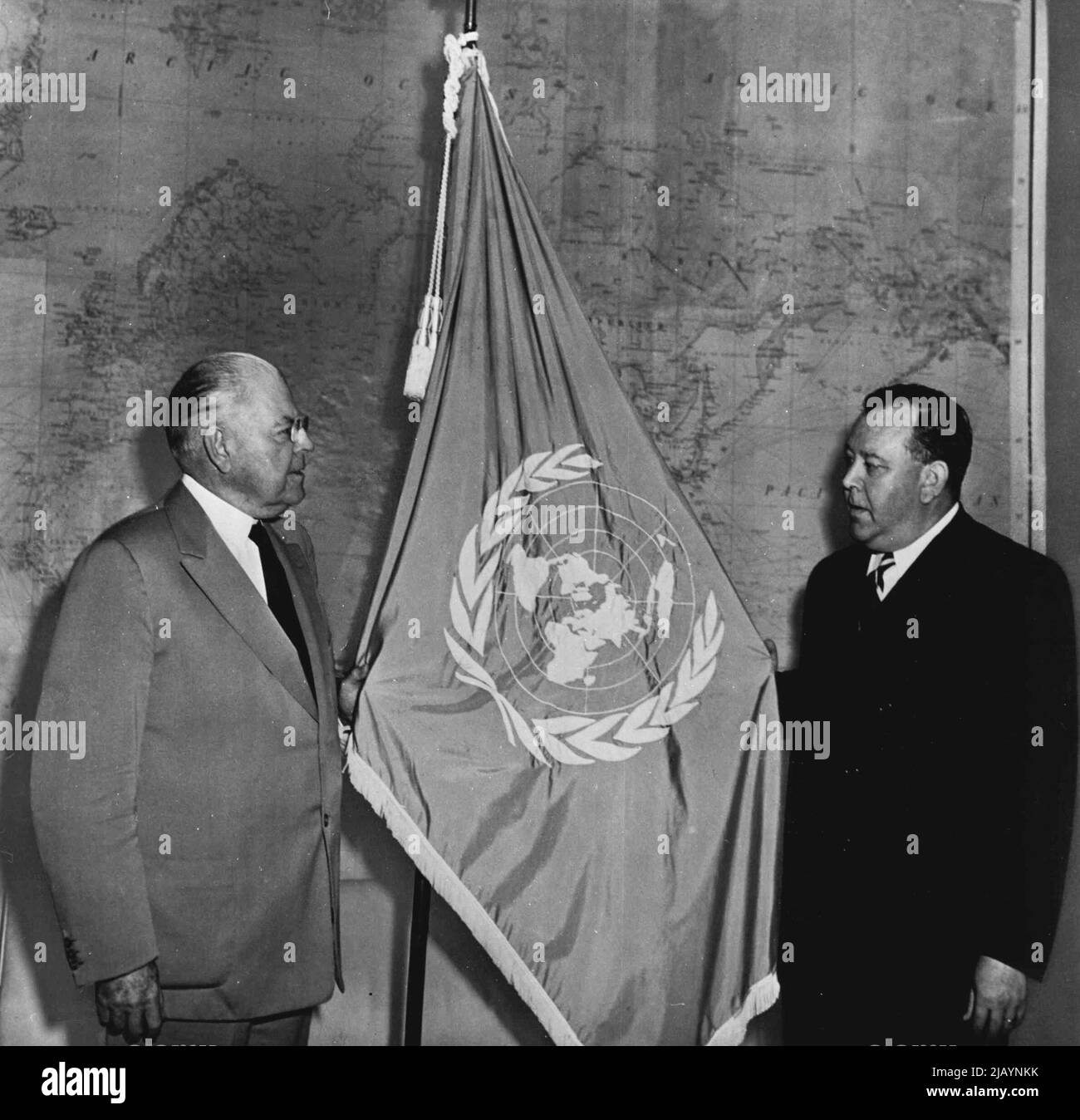 Trygve lie (à droite), Secrétaire général de l'Organisation des Nations Unies, présente le drapeau bleu et blanc de l'Organisation des Nations Unies à l'Ambassadeur Warren Austin, représentant des États-Unis auprès de l'Organisation des Nations Unies. Jusqu'à ce que la paix soit rétablie en Corée, ce drapeau flottera au quartier général du général Douglas MacArthur; l'Armée des États-Unis, commandant général des forces militaires unifiées des Nations Unies qui aident la République de Corée à se défendre contre l'invasion communiste nord-coréenne. 08 juillet 1950. (Photo par United States information Service). Banque D'Images