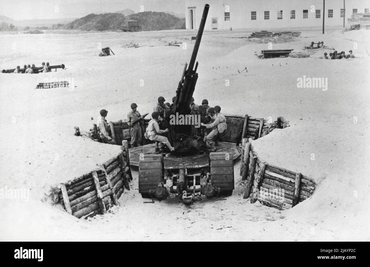 U. S. batterie anti-avion - montre l'équipe en action -- l'équipage d'un 90 mm. Pièce anti-avion de l'armée américaine est prêt à passer à l'action. Situé dans des fosses fortement barricadées à travers le sable peut être vu la hauteur de recherche (à gauche), de la direction de recherche (à droite) et le poste de commandant de batterie et de l'officier de gamme. L'équipage du canon a élevé son arme, les porte-munitions et le chargeur sont prêts avec des obus et le tireur a sa main sur la gâchette. 08 février 1943. (Photo d'Interphoto News Pictures, Inc.). Banque D'Images