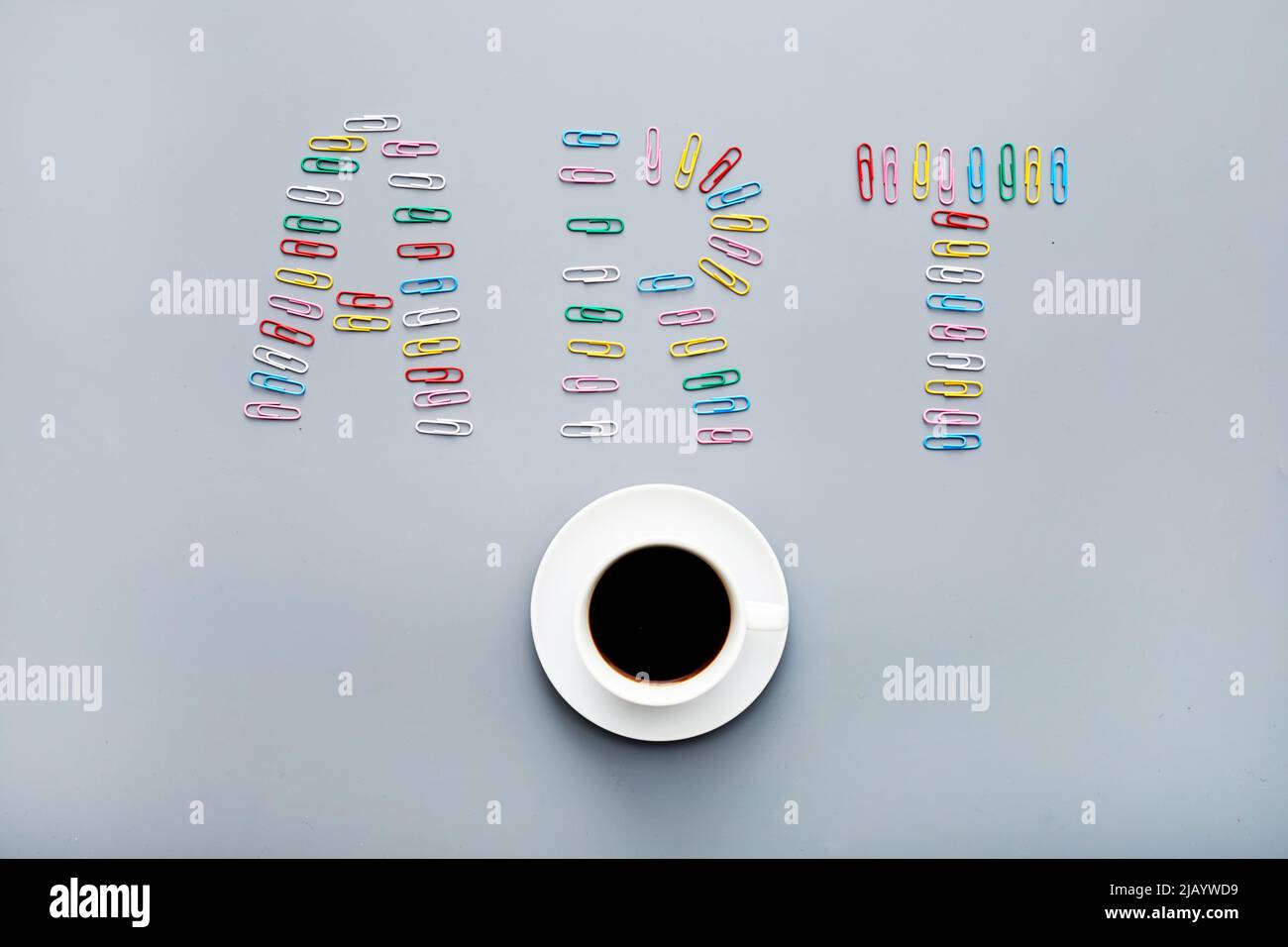 Concept d'art moderne : directement au-dessus de la vue des trombones colorés disposés en forme d'inscription artistique et de tasse à café Banque D'Images