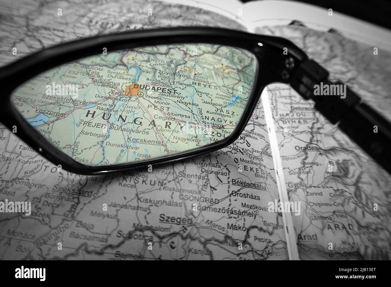 Une image créative montrant le pays de Hongrie et la ville de Budapest sur une carte à travers la lentille des lunettes de lecture. Noir et blanc avec mise au point des couleurs Banque D'Images