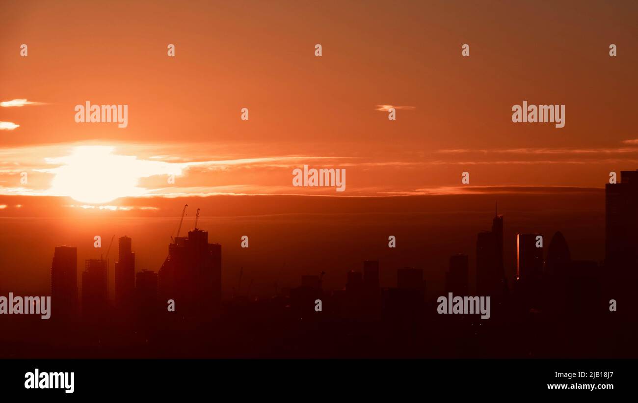 Vue aérienne du lever du soleil sur les gratte-ciel de Londres avec des silhouettes décapeuses contre un ciel orange vif. Banque D'Images