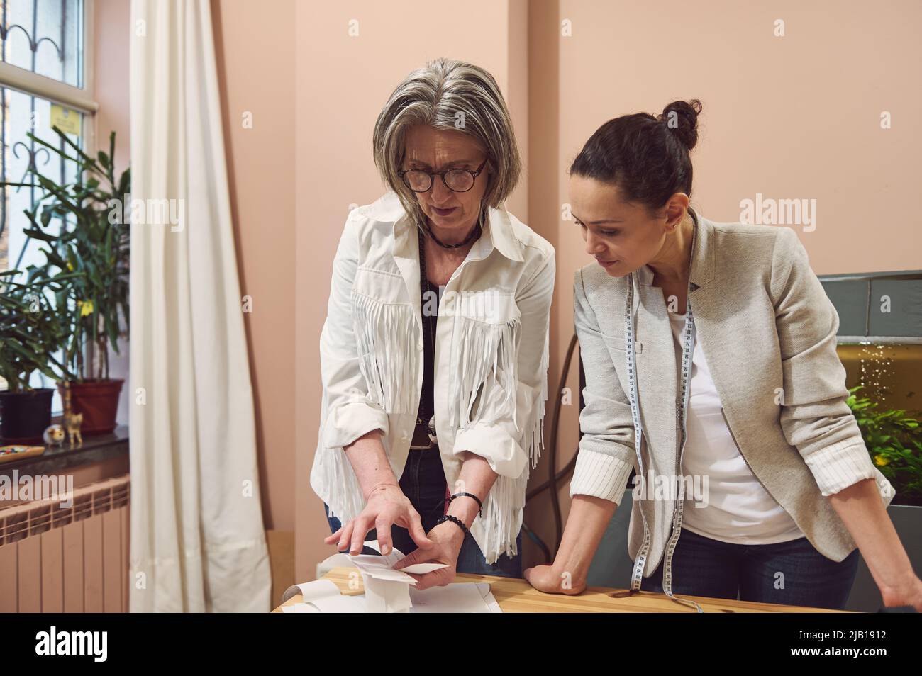 Une équipe assidue de créateurs de mode travaillant dans un studio de création de mode discutant des modèles pour coudre des vêtements dans un atelier de personnalisation. Couturière, queue Banque D'Images