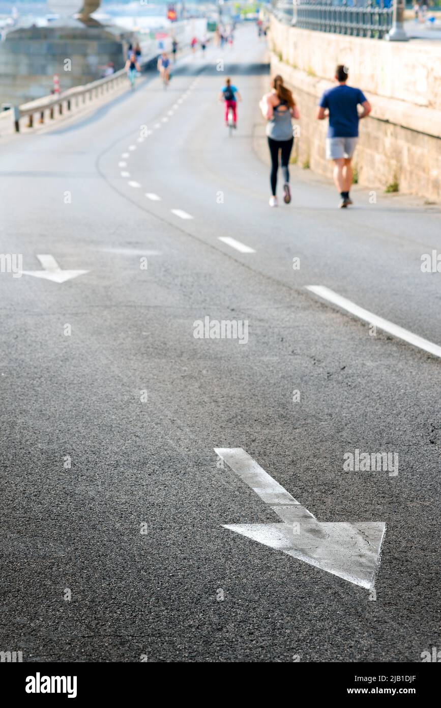 La flèche sur l'asphalte, les gens non focalisés courant dans la rue Banque D'Images