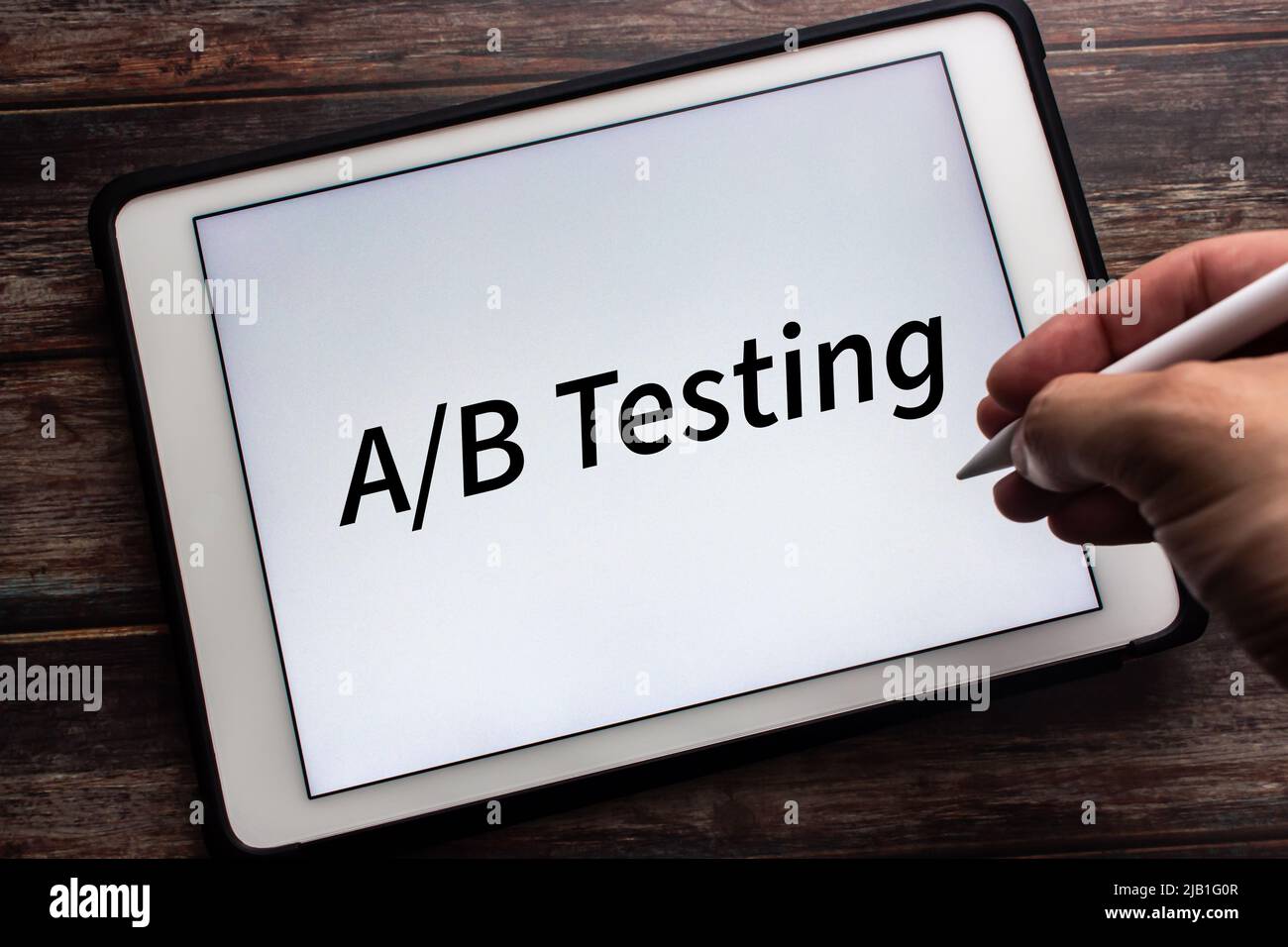 Tablette affichant “Test A/B” sur fond blanc. Homme tenant le stylet dans l'image. Le test a/B est une méthodologie de recherche d'expérience utilisateur Banque D'Images