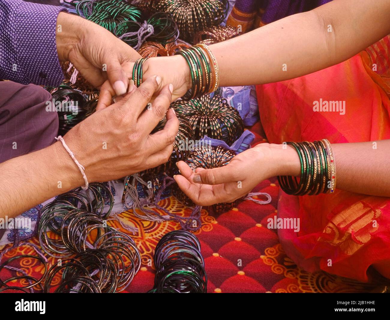 Cérémonie de pré-mariage une femme bangle vendeur est de mettre des bangles de verre vert, la culture indienne. Banque D'Images