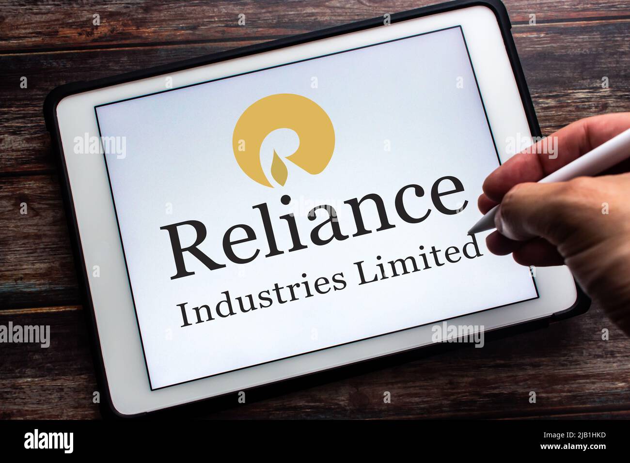 Kumamoto, JAPON - juillet 9 2021 : logo de la société indienne Conglomérat Reliance Industries Limited (RIL) sur tablette. Homme main tenant un stylo. Banque D'Images