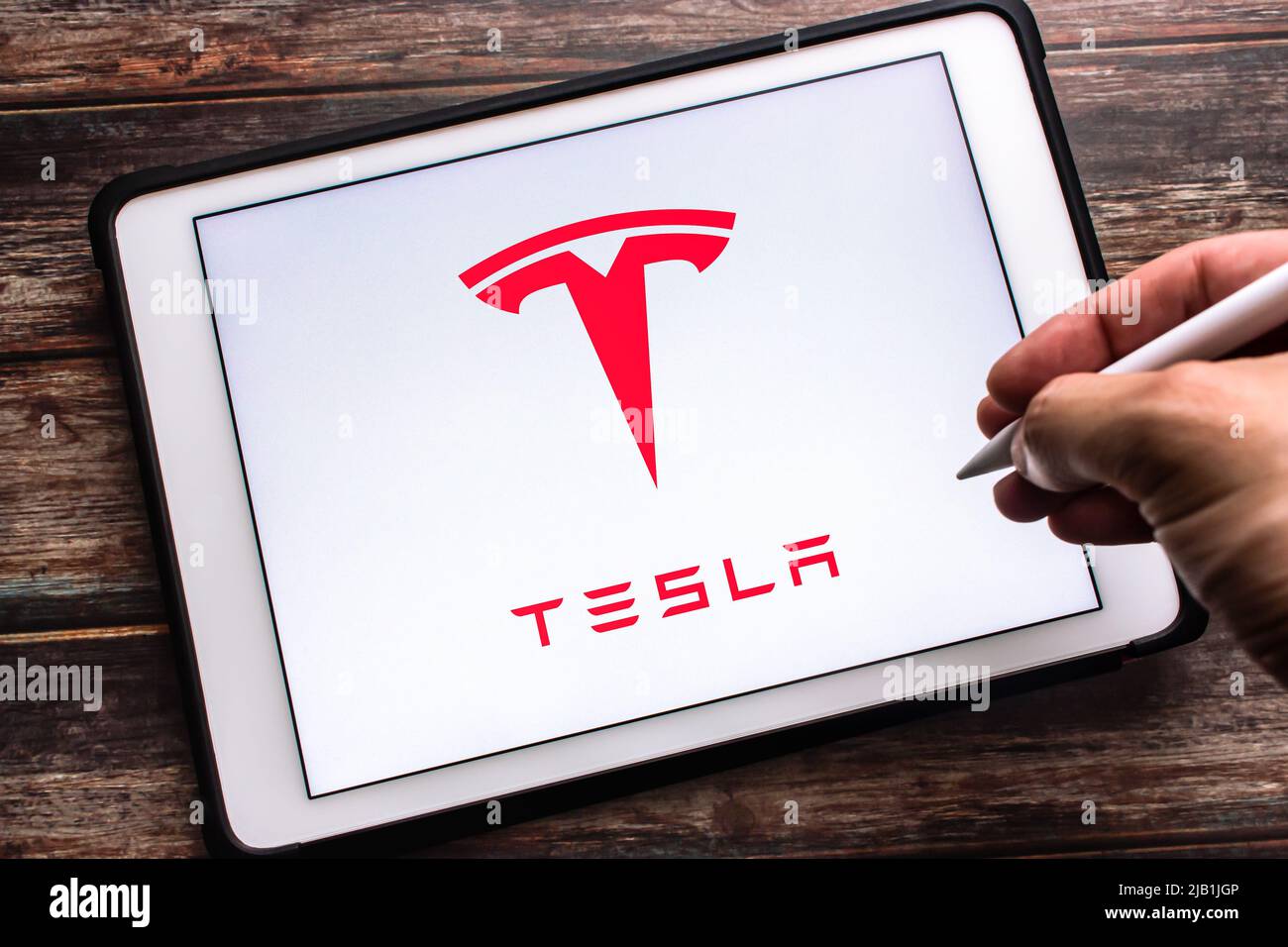 Kumamoto, JAPON - juillet 27 2021 : le logo de la société américaine de véhicules électriques et d'énergie propre Tesla, Inc. Sur tablette. Main tenant le stylet sans fil. Banque D'Images